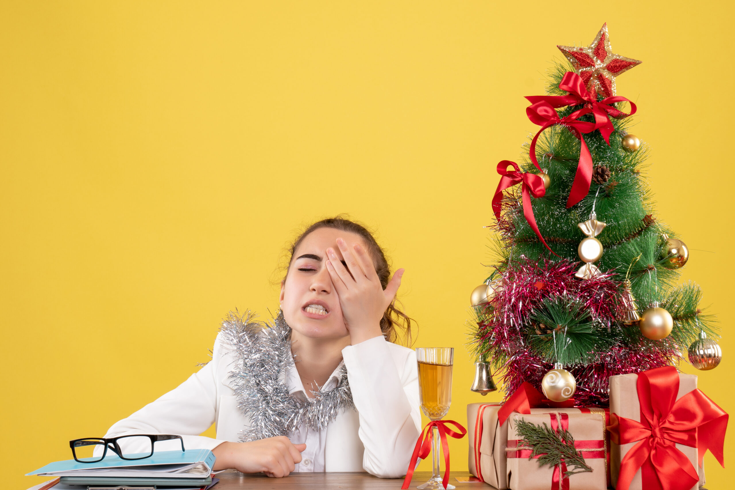 front view female sitting at table stressed yellow background with Christmas tree gift boxes